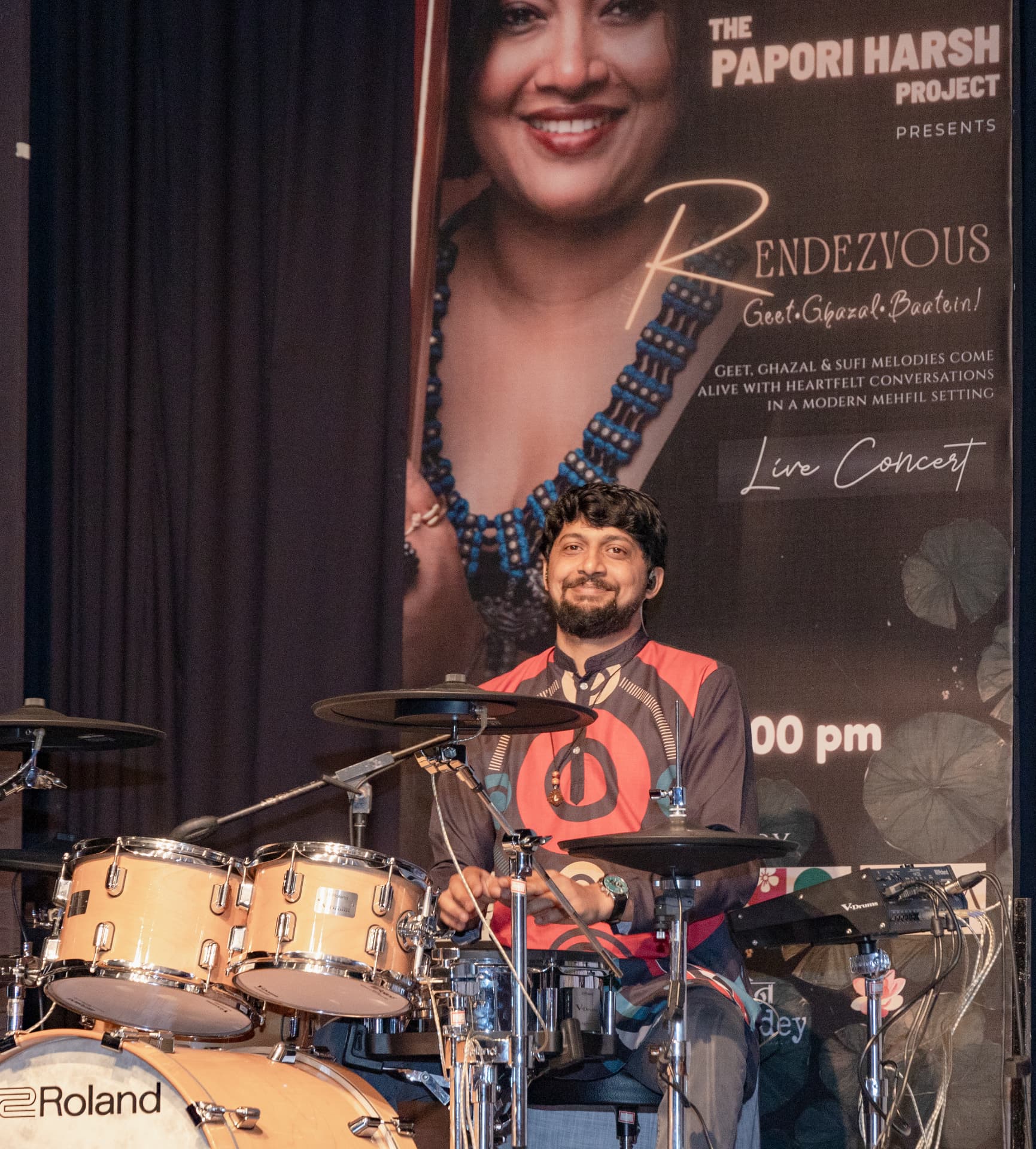 The drummer smiling on stage in front of the Rendezvous backdrop